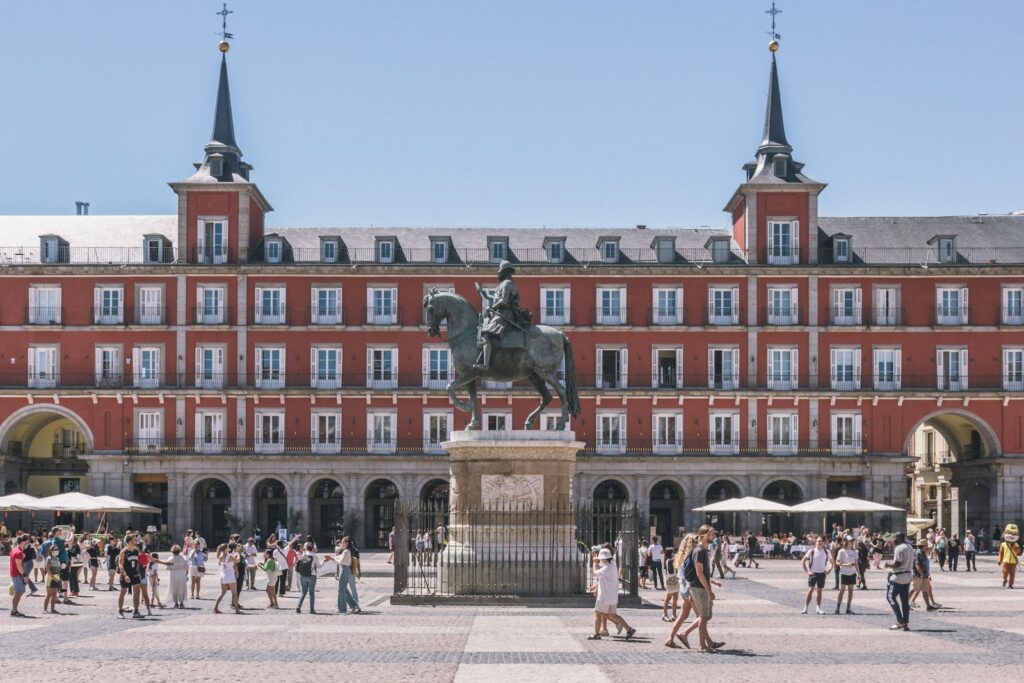 a large building with a statue in front of it with Plaza Mayor, Madrid in the background